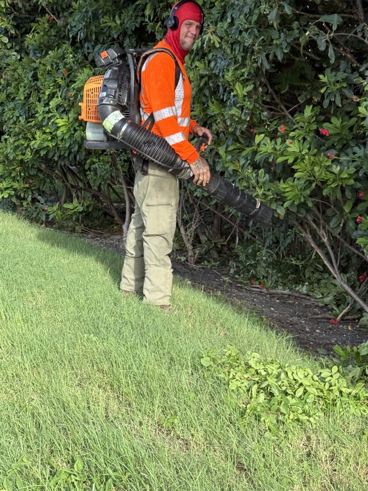 Landscaper wearing a backpack leaf blower and high-visibility shirt working outside in the Florida heat